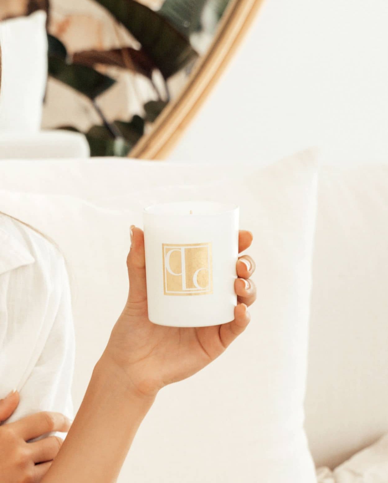 Caitlin Louise Collection Signature Collection Scented Candle - held in model's hand - white lounge in background