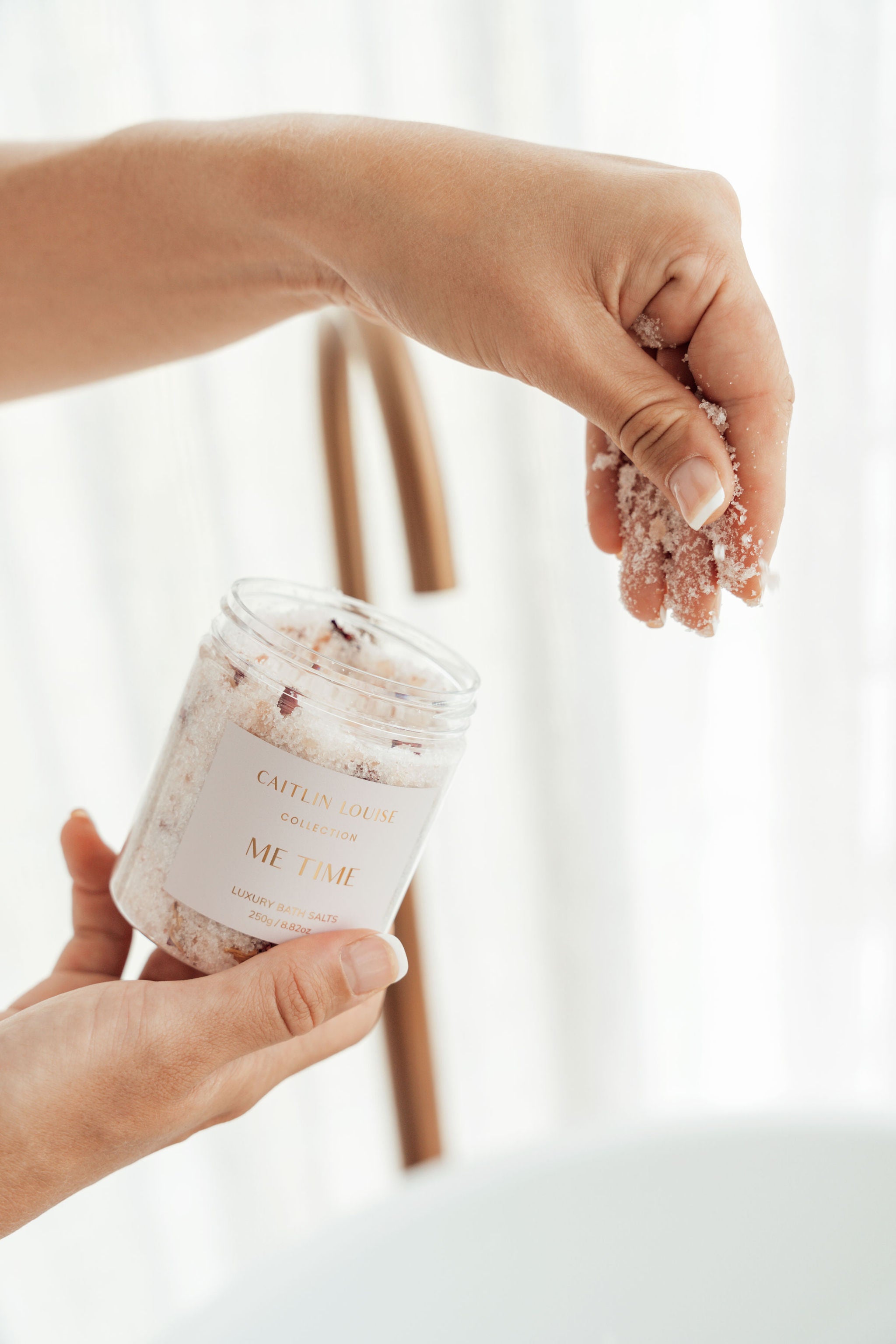 Hand sprinkling luxury bath salts into the bath.