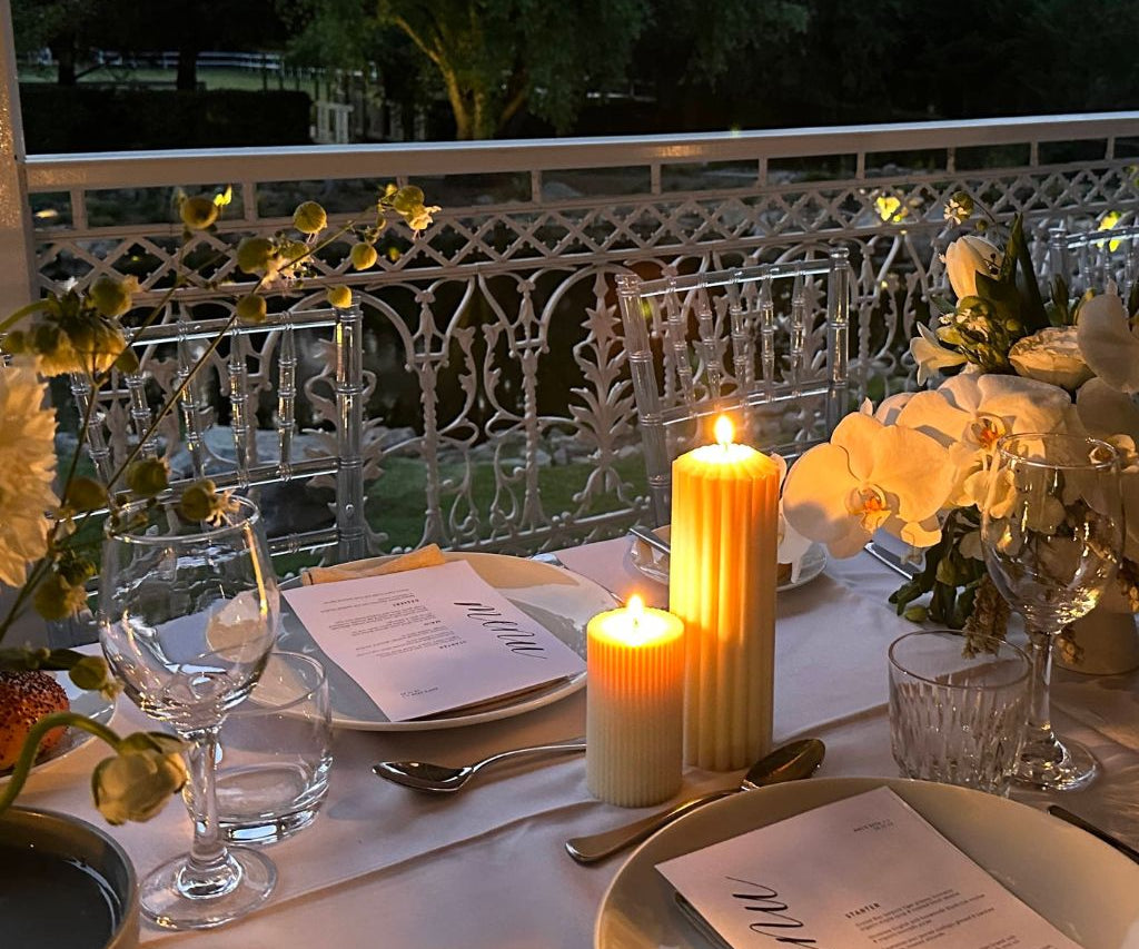 Caitlin Louise Collection Lumiere and Harmonia Pillar Candles styled on table at dinner party - lit with flame