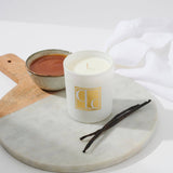 Caitlin Louise Collection Vanilla Caramel Scented Candle on board with bowl of caramel in background and vanilla sticks in the foreground.