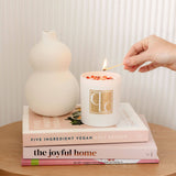 Champagne Sunset crystal infused candle on stack of books - hand holding lit match to light the wick