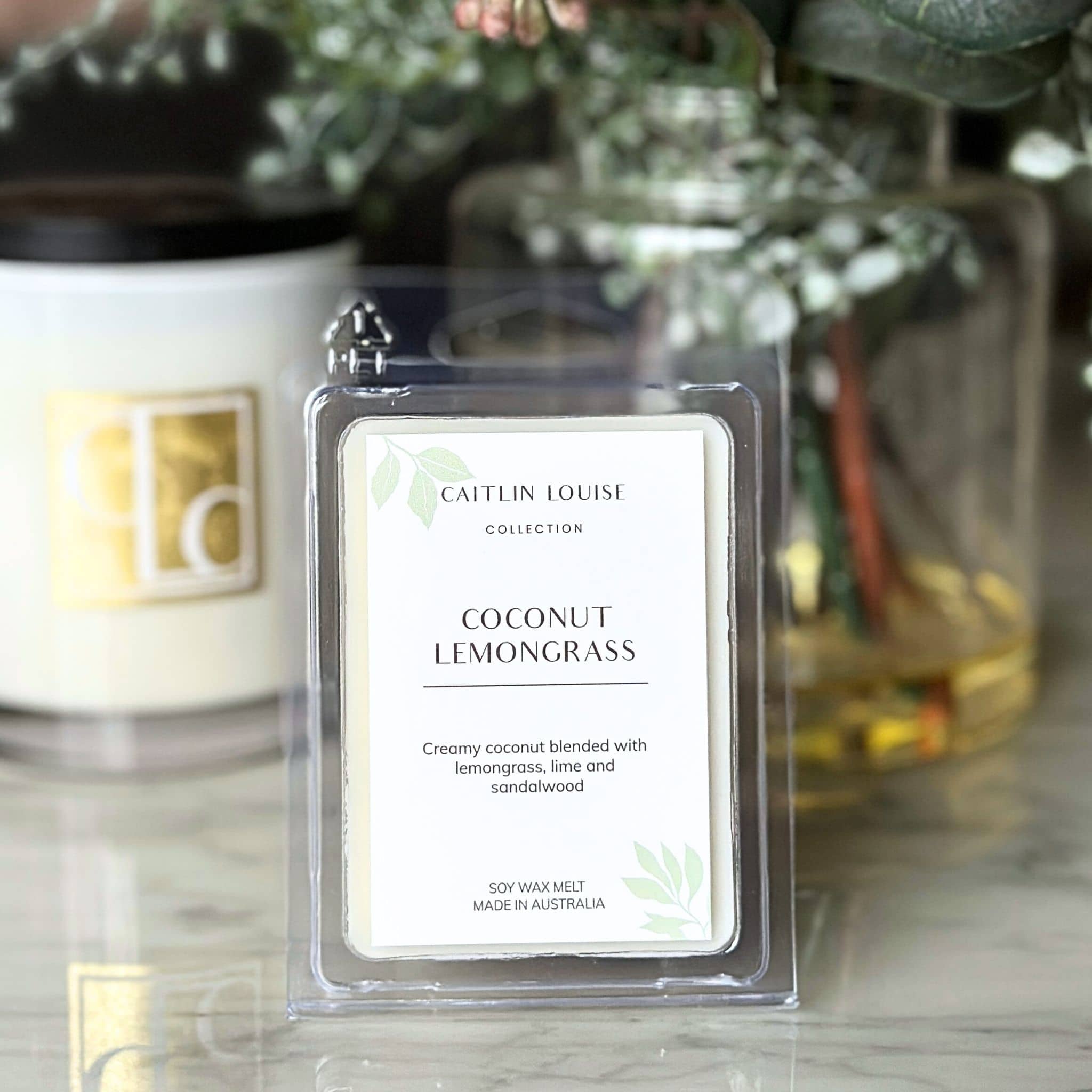 Coconut Lemongrass wax melt packaging with a blurred background of candles and plants