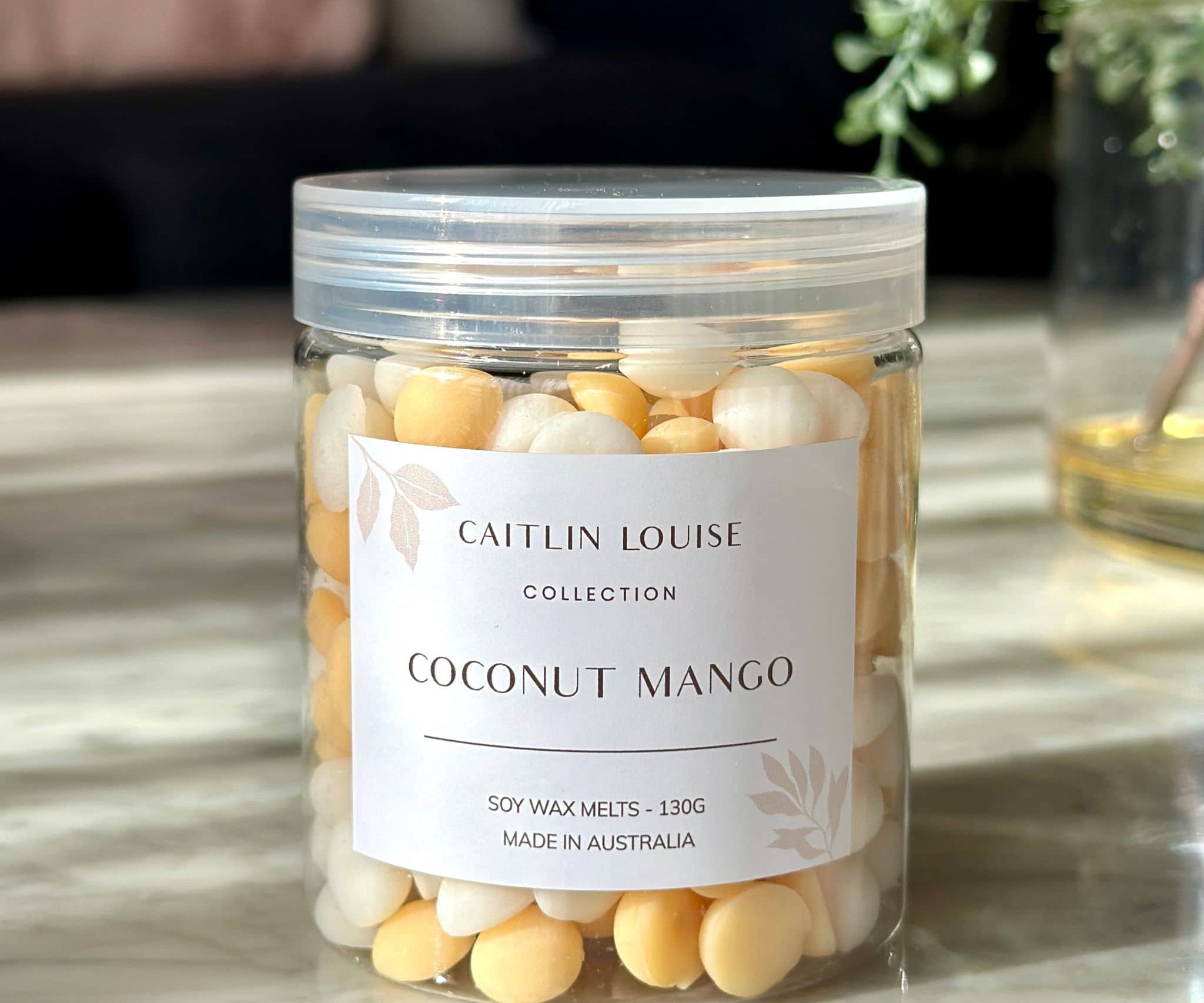 Caitlin Louise Collection's Coconut Mango Soy Wax Melt Pebbles - on coffee table.