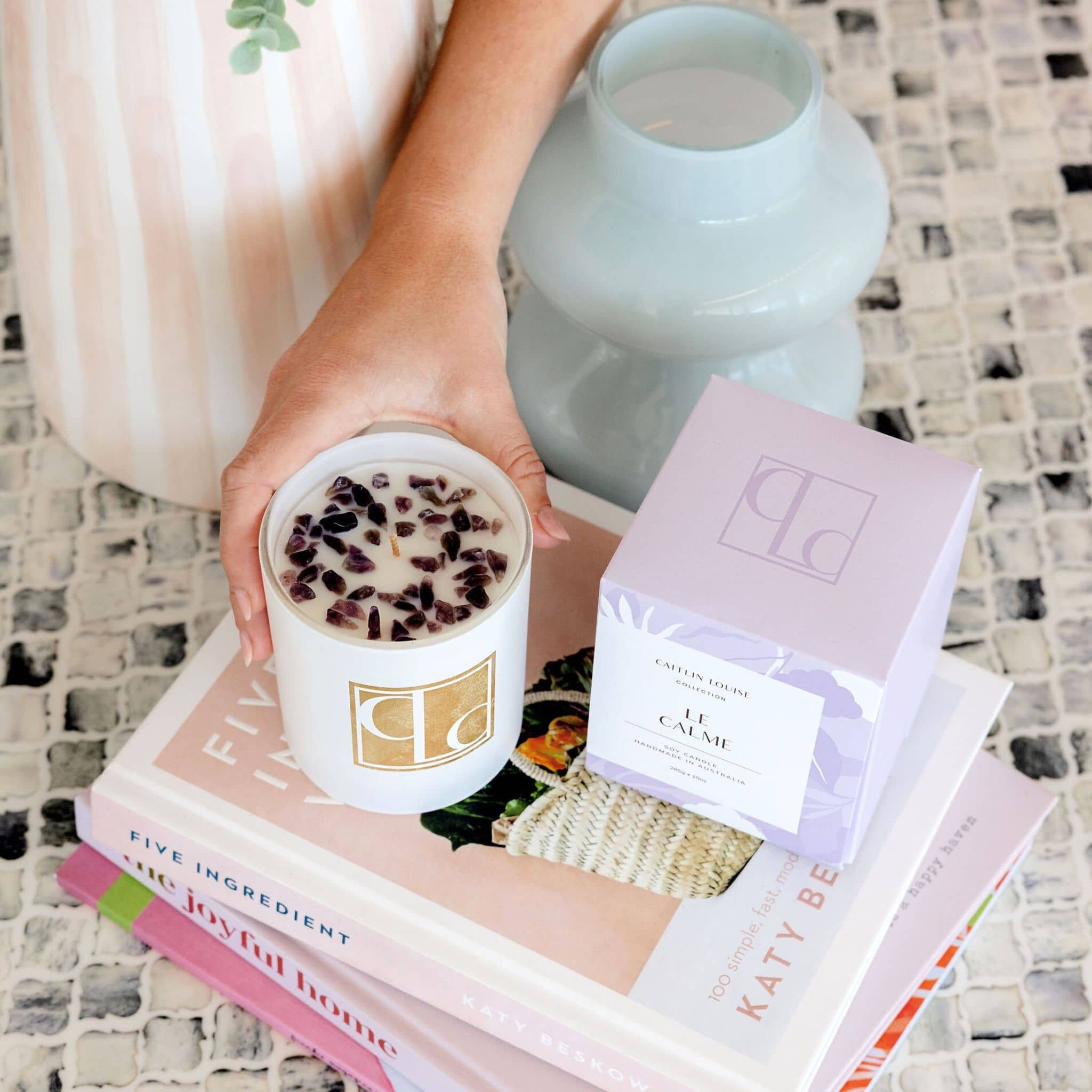 Le Calme calming crystal infused candle on stack of books on coffee table