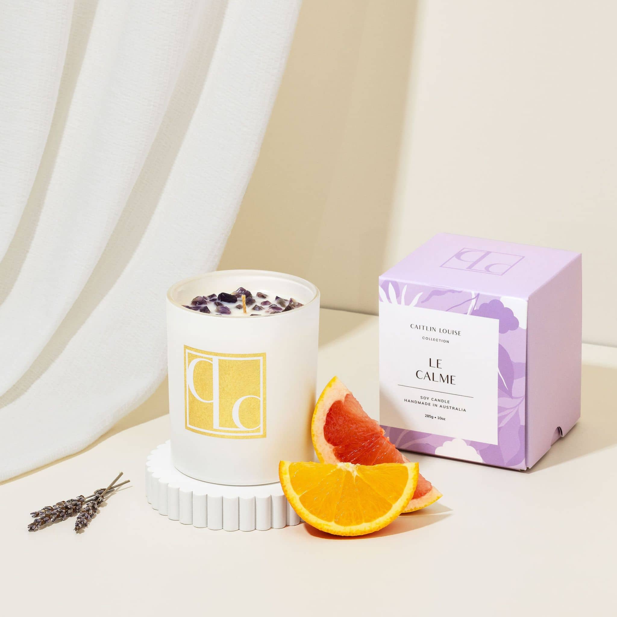 Amethyst crystal infused candle with decorative elements on a neutral background