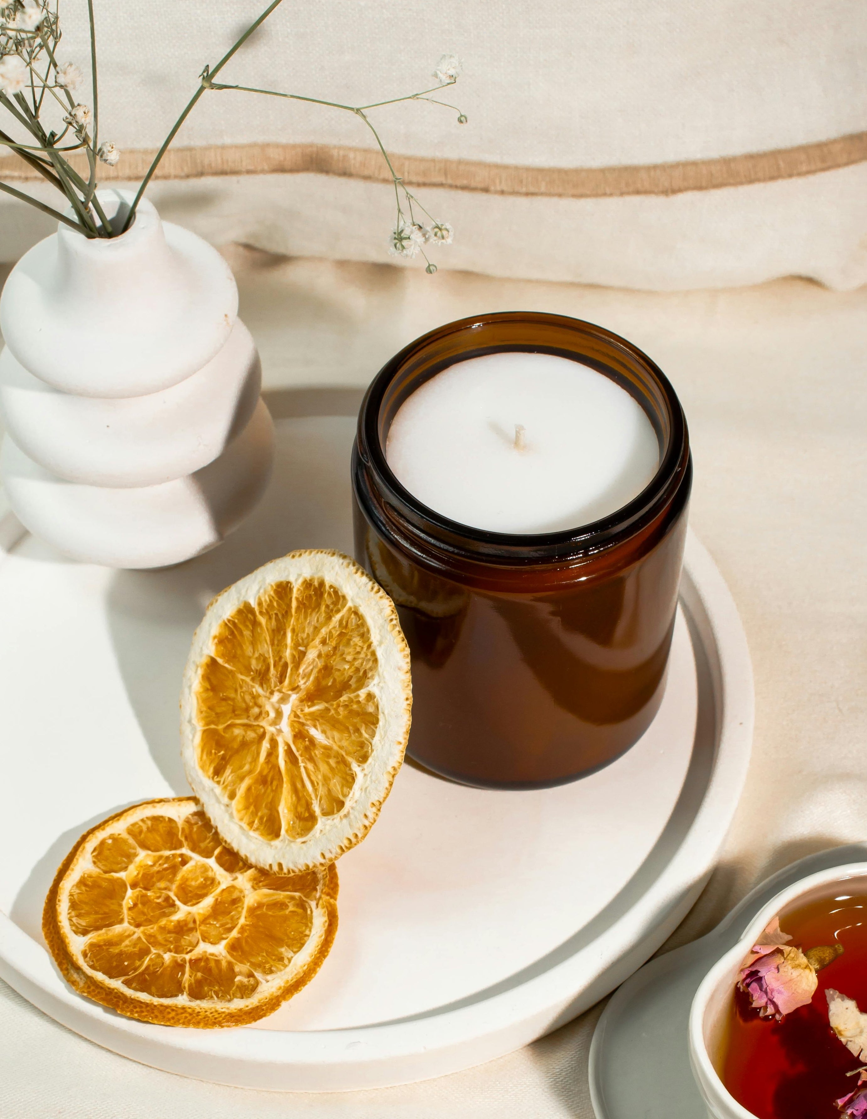 Private label candle manufacturing - amber jar on tray with citrus slices