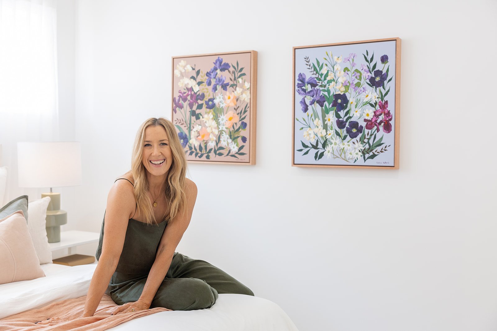 Prudence De Marchi sitting on a bed with floral wall art in the background
