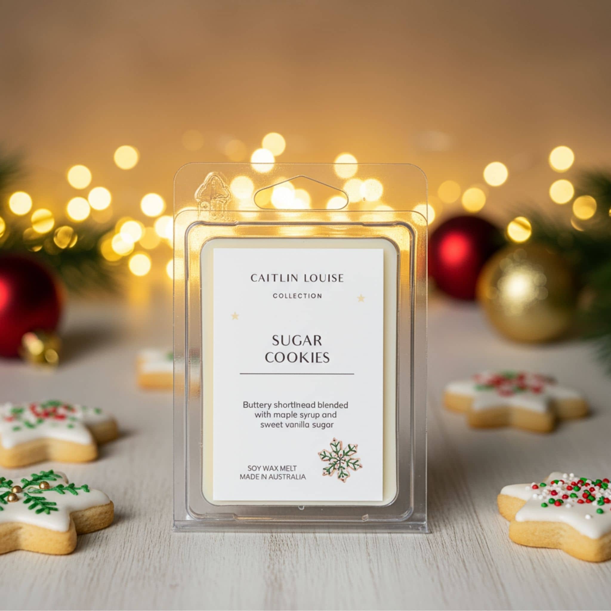 Wax melt packaging labeled 'Sugar Cookies' by Caitlin Louise with Christmas decorations in the background.