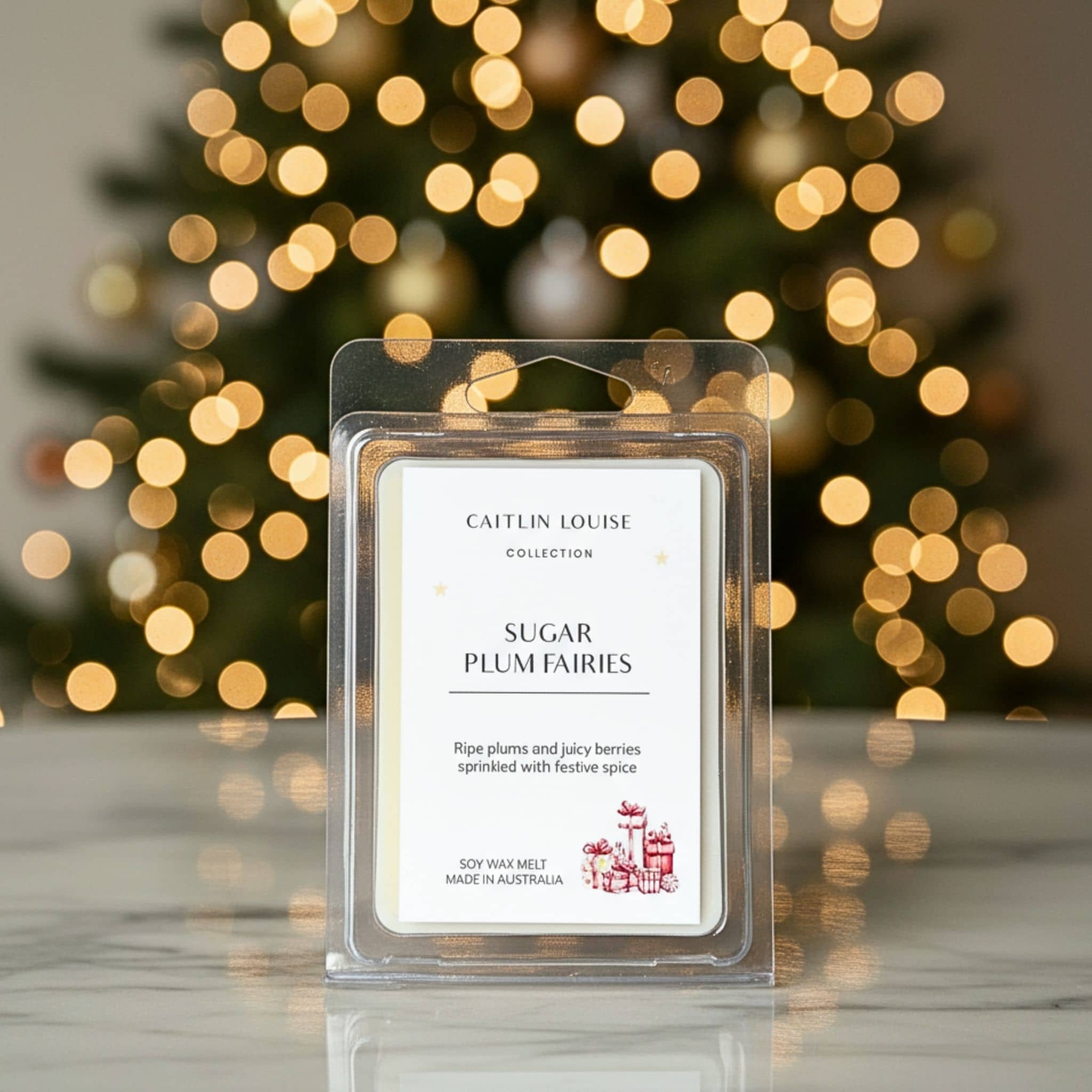 Caitlin Louise Sugar Plum Fairies wax melt packaging with a blurred Christmas tree in the background