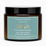 Amber glass jar candle with a black lid and a dusty teal label that reads 'CAITLIN LOUISE COLLECTION' and 'TOO MANY BOOKS? YOU MEAN NOT ENOUGH SHELVES'.