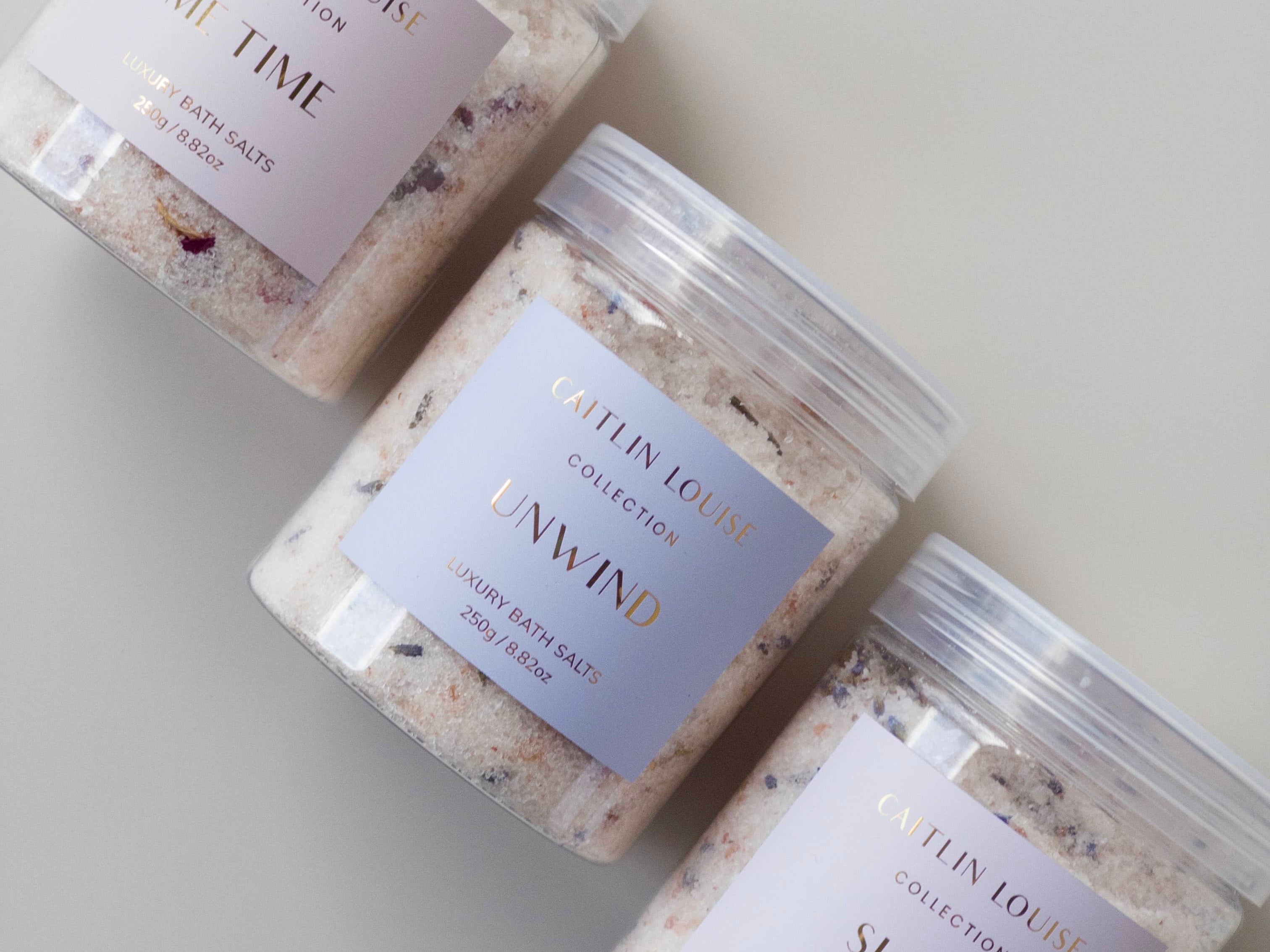 Flat lay of Caitlin Louise Collection's range of luxury bath salts. Showing Me Time, Unwind and Sleep on neutral background.