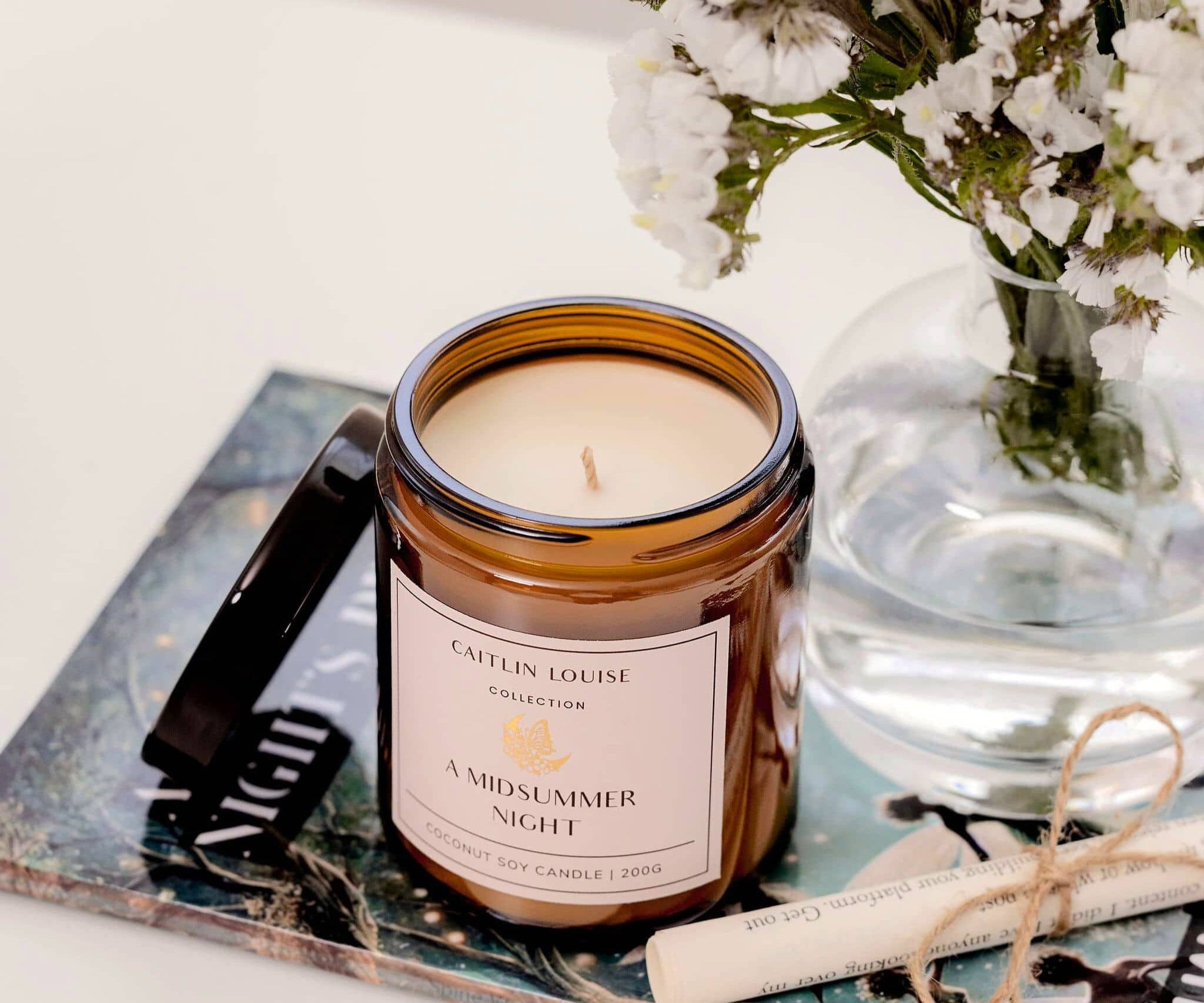 Caitlin Louise Collection A Midsummer Night Bookish Candle - styled on book with scroll and flowers