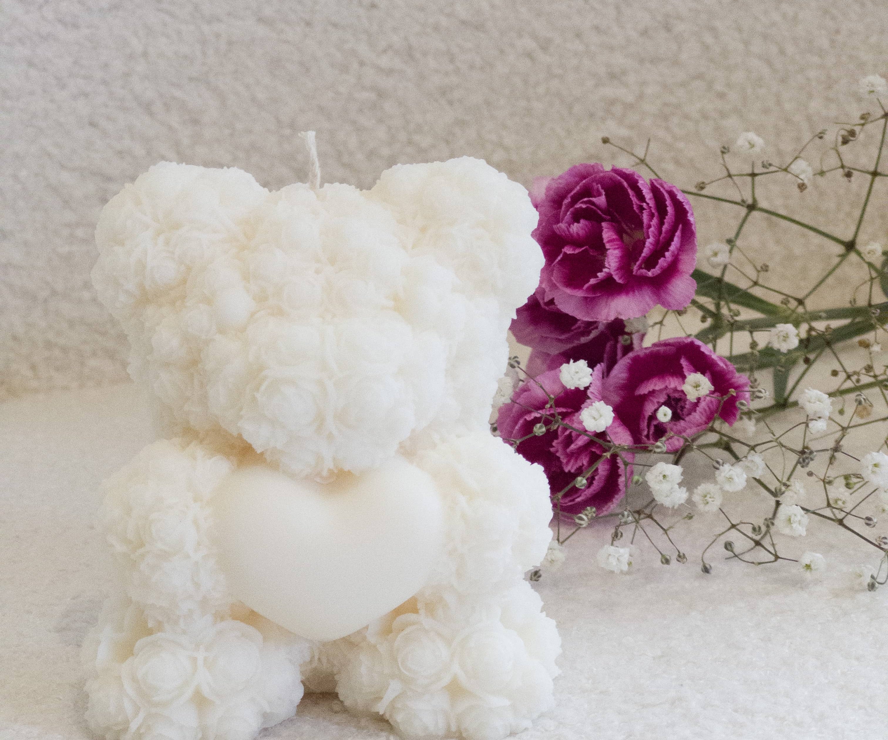 Caitlin Louise Collection sculptural bear candle holding a heart - purple flowers in the background.