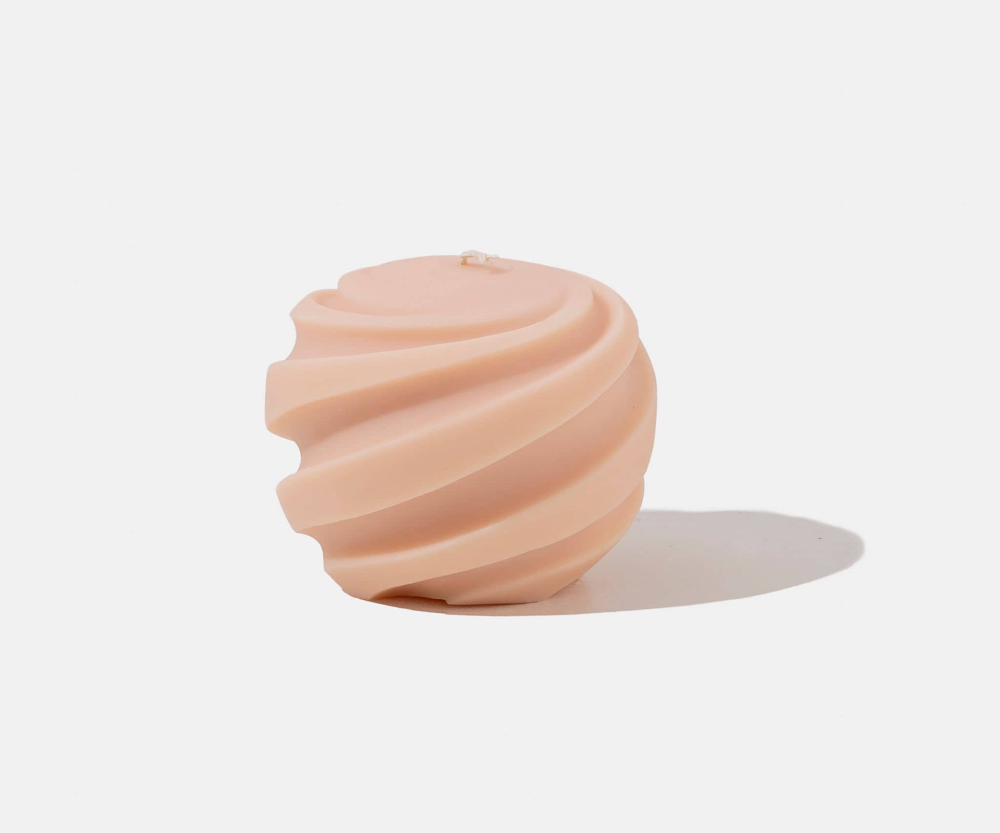 Apricot coloured spiral shaped candle - white background