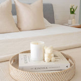 Caitlin Louise Collection salty caramel kiss soy candle styled with Aria sculptural candle on a book and tray - on a bed in a beautiful bedroom.