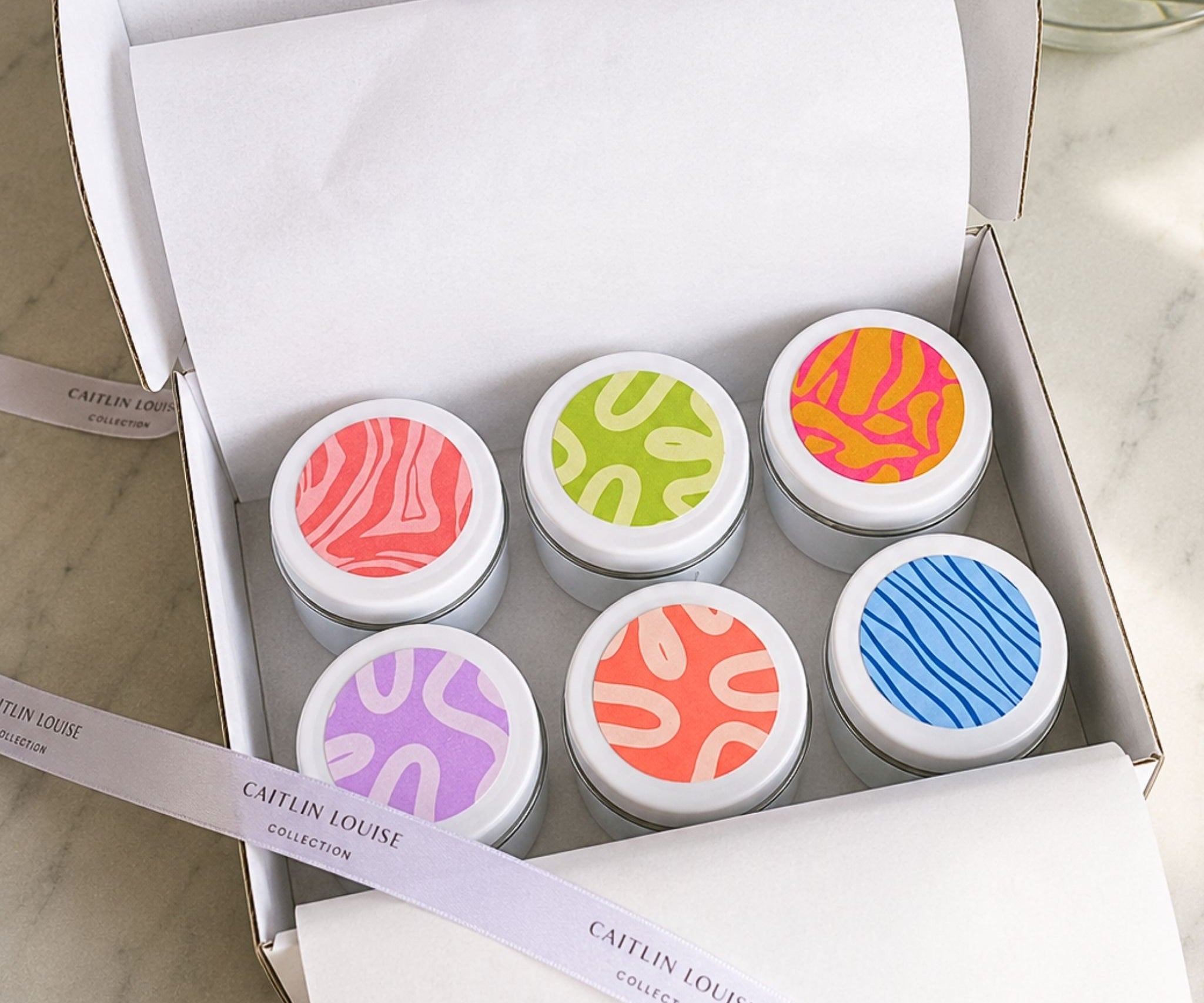 Signature Collection discovery set mini candle tins in a white box with tissue paper and ribbon