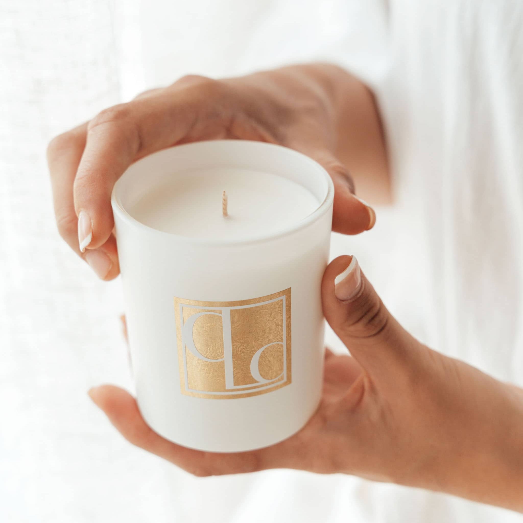 Hands holding Caitlin Louise Collection Signature range scented mini candle with white background