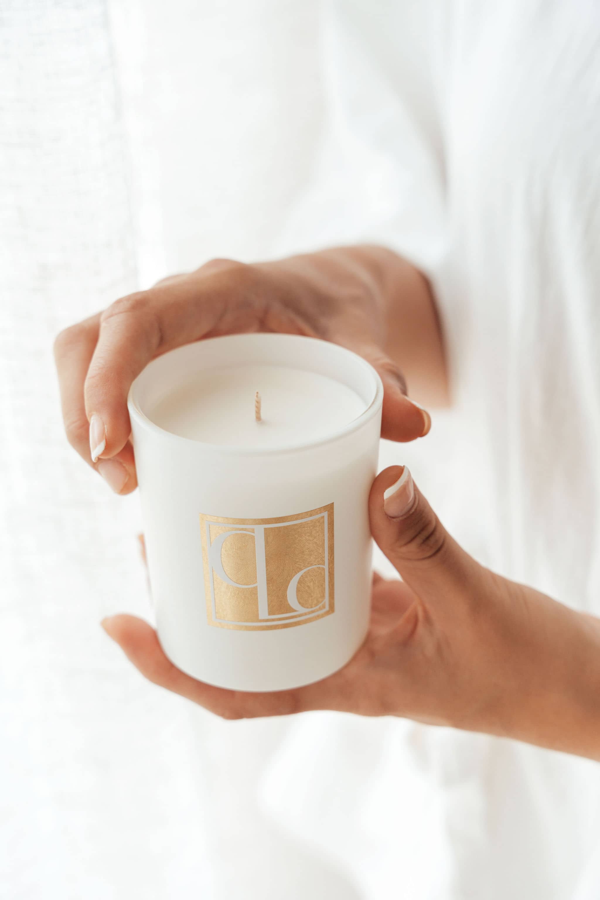 Hands holding Caitlin Louise Collection Signature range scented mini candle with white background