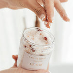 Hand reaching into Caitlin Louise Collection's Me Time Luxury Bath Salts showing the salts and rose petals inside.