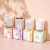 four caitlin louise collection luxury scented candles lined up with the candle sitting on top of the box.