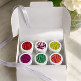 Colourful discovery set candle tins in a white box with tissue paper and ribbon