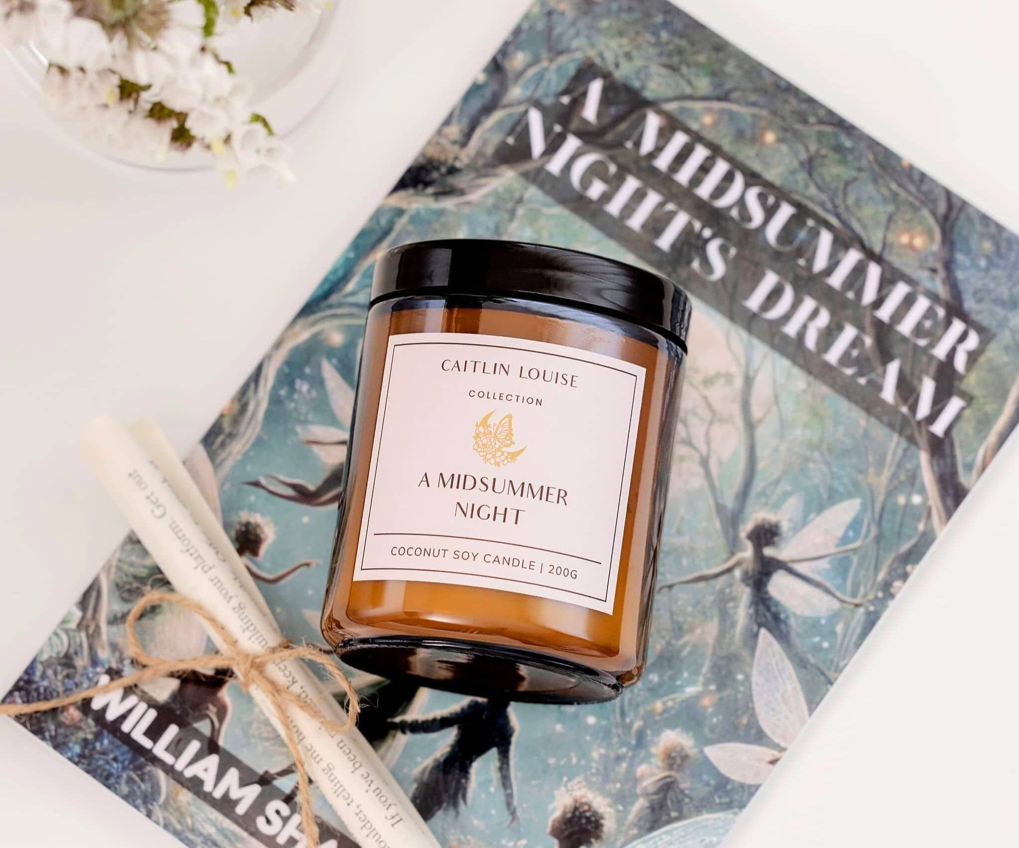Caitlin Louise Collection A Midsummer Night Bookish Candle - styled on book with scroll and flowers - birds eye view