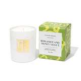 Candle with a green and yellow box labeled 'Bergamot and Honey Velvet' on a white background