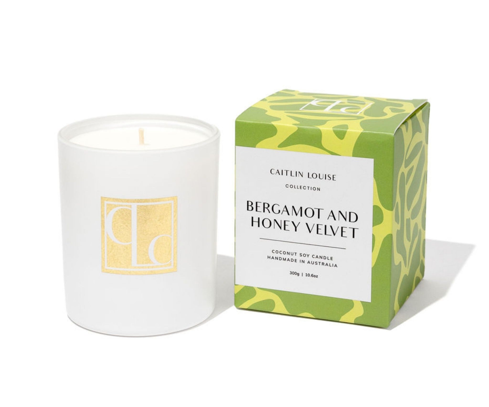 Candle with a green and yellow box labeled 'Bergamot and Honey Velvet' on a white background