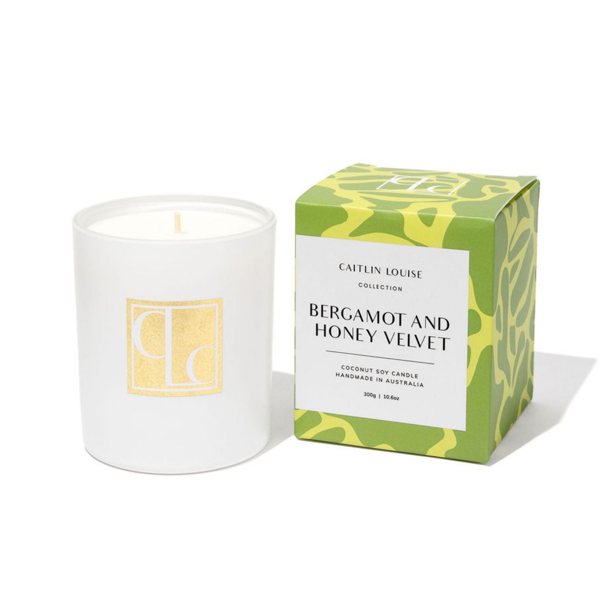 Candle with a green and yellow box labeled 'Bergamot and Honey Velvet' on a white background