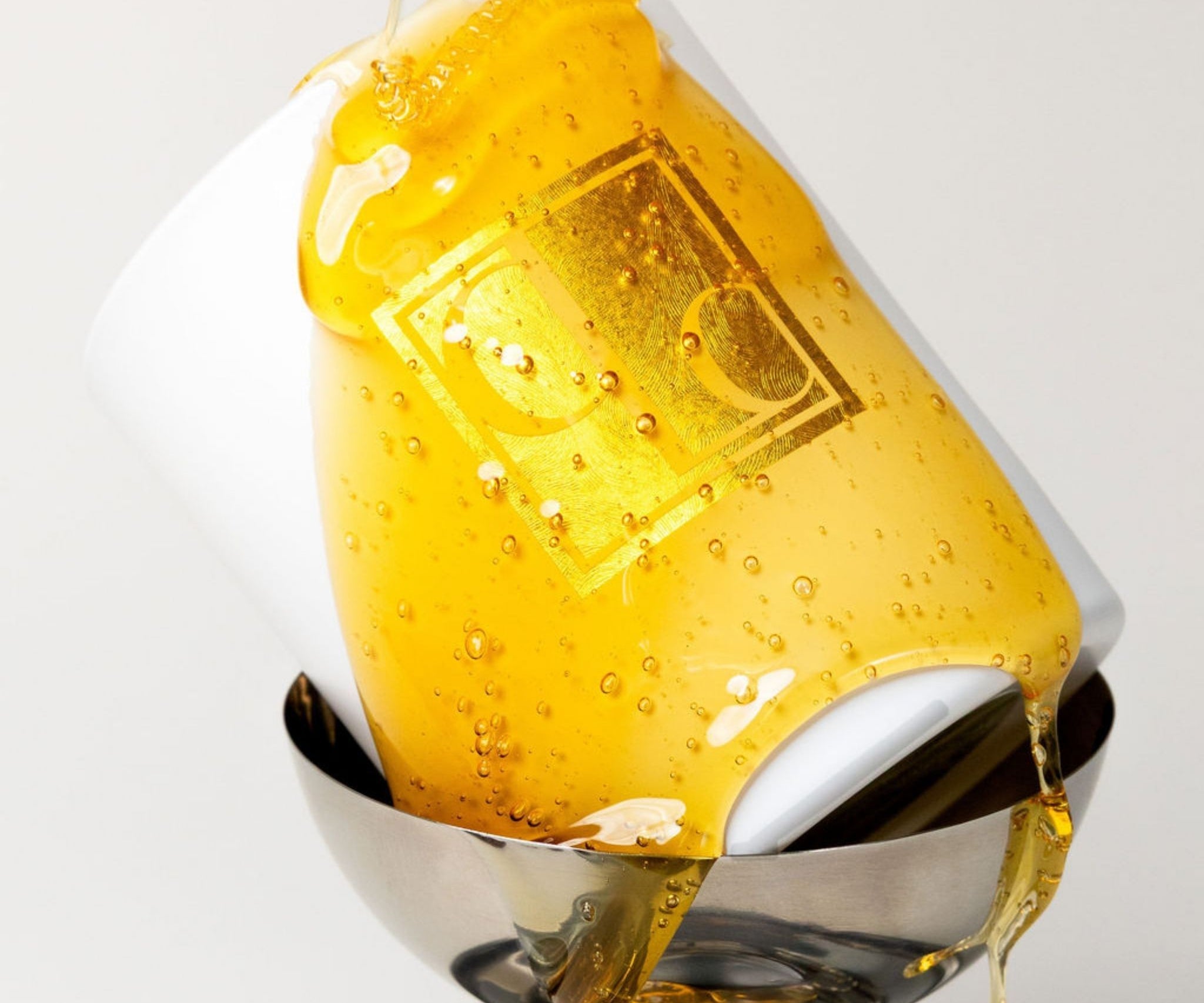 Close-up of a Caitlin Louise Collection candle drizzled with runny honey, with a focus on the bubbles.