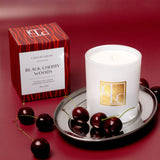 Candle with packaging and cherries on a red background