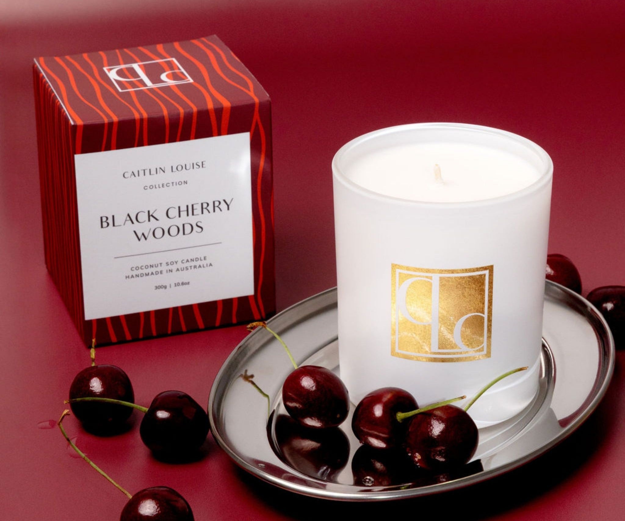 Candle with packaging and cherries on a red background