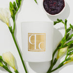 Blackcurrant and white musk scented candle flat lay with blackcurrant jam and freesias