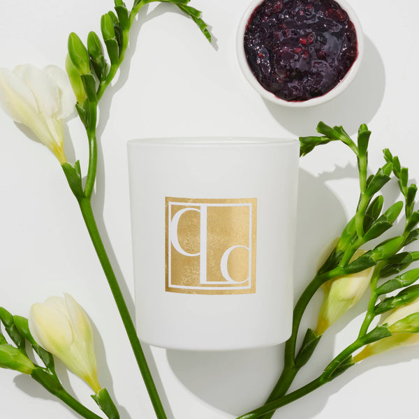 Blackcurrant and white musk scented candle flat lay with blackcurrant jam and freesias