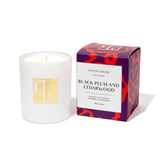 Caitlin Louise Collection white candle with a decorative box labeled 'Black Plum and Cedarwood' on a white background