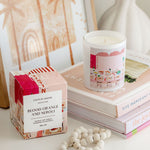 Candle and packaging with 'Blood Orange and Neroli' on a stack of books.