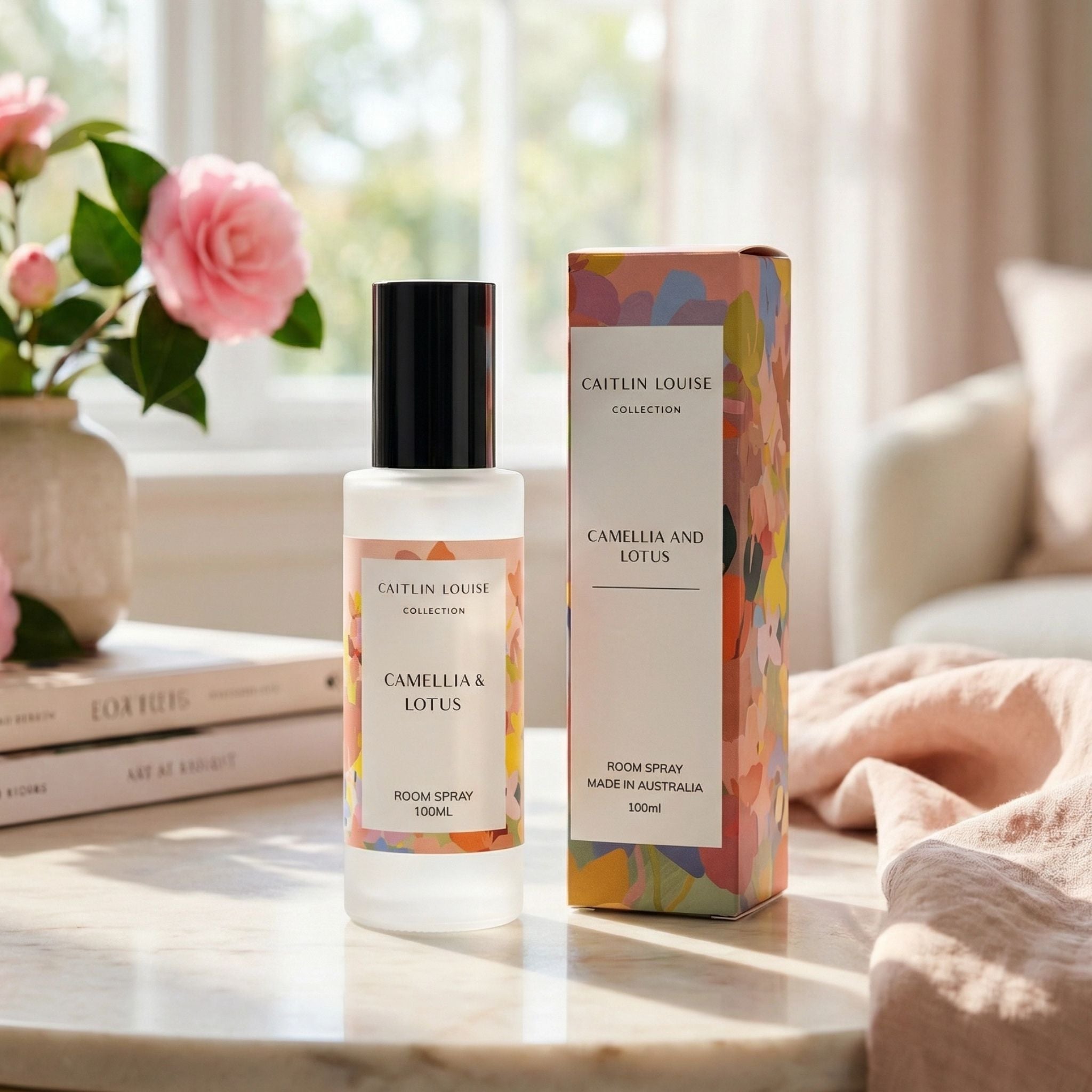 Caitlin Louise Camellia and Lotus room spray bottle and packaging on a table with flowers in the background