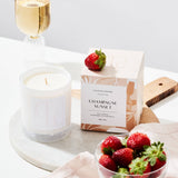 Champagne sunset candle styled with champagne and strawberries