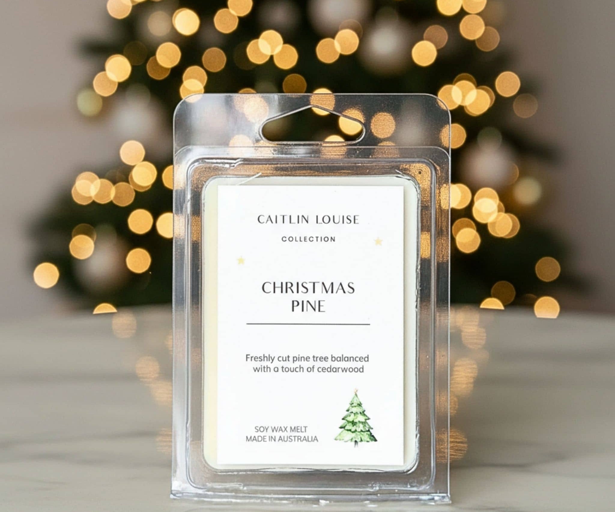 Caitlin Louise Collection Christmas Pine wax melt with blurred Christmas tree lights in the background