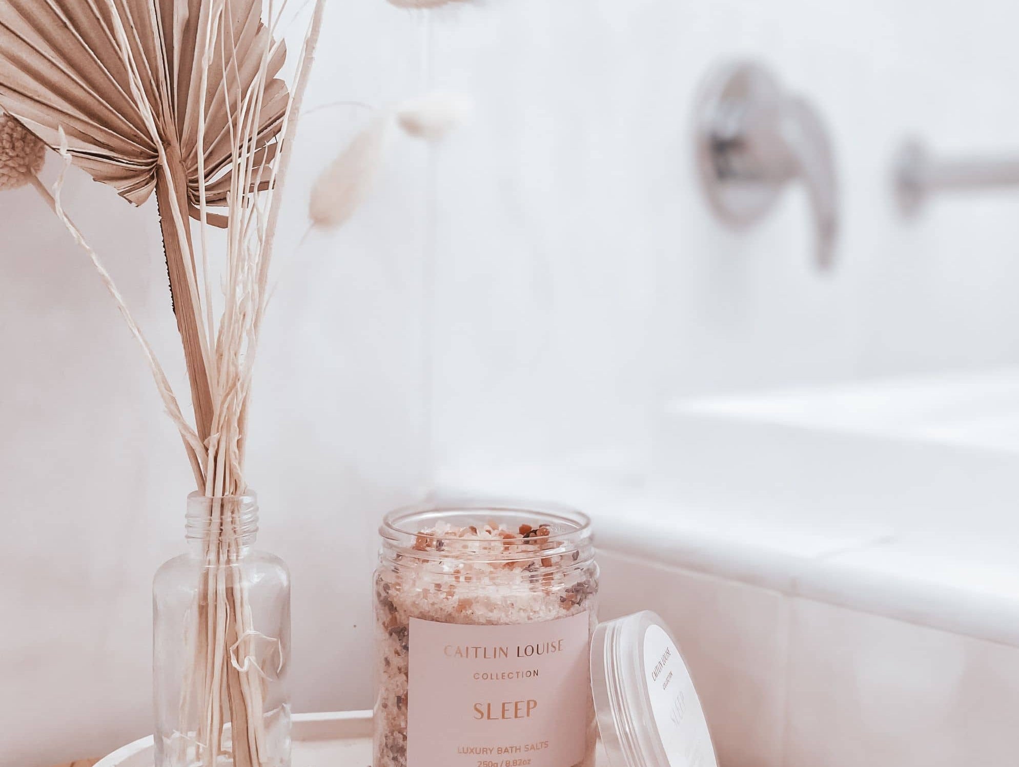 Caitlin Louise Collection Sleep Bath Salts styled on tray next to bath