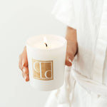 Close up of hand holding Bijou candle, white background