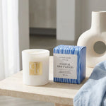 Coastal Driftwood candle and packaging on a wooden surface with a neutral background