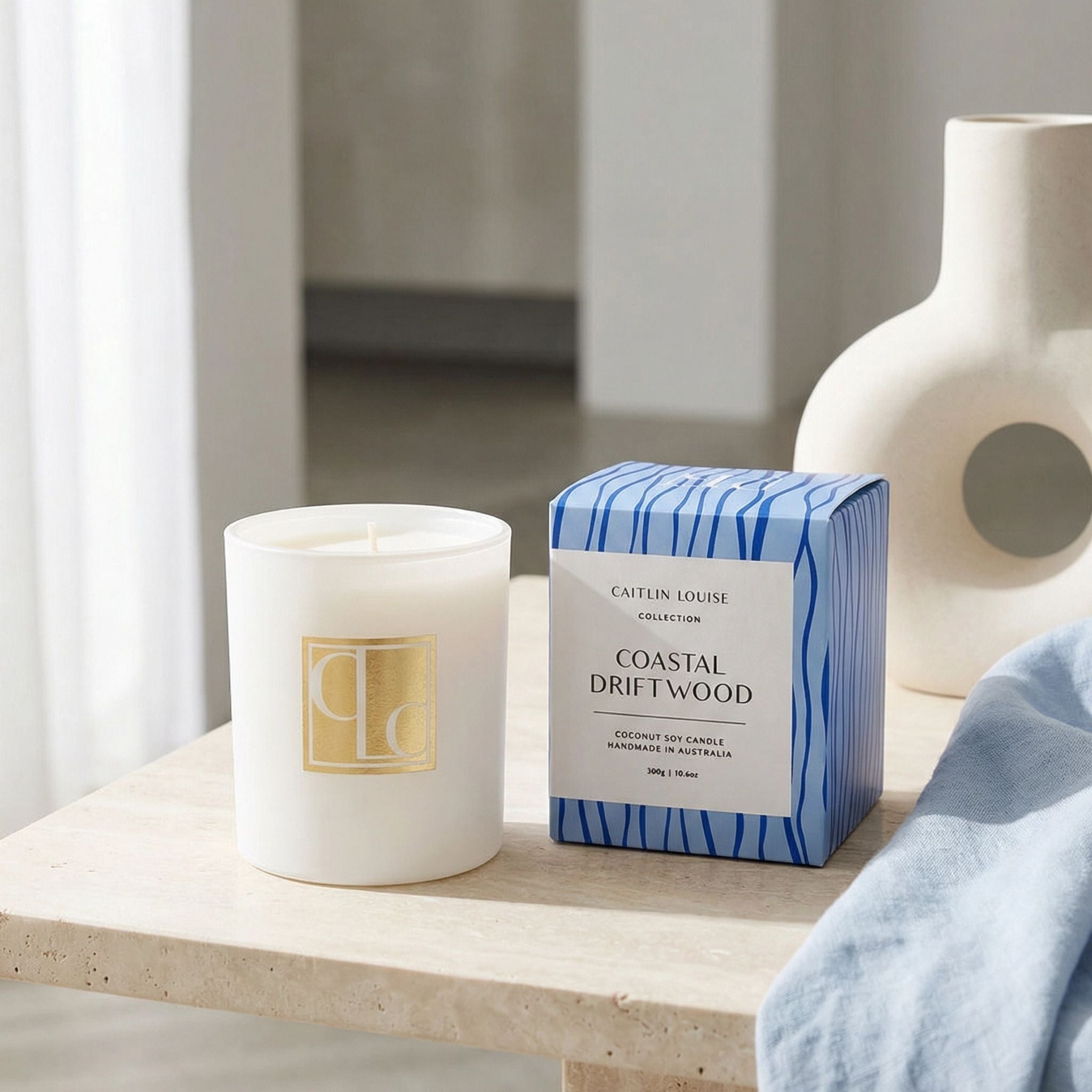 Coastal Driftwood candle and packaging on a wooden surface with a neutral background
