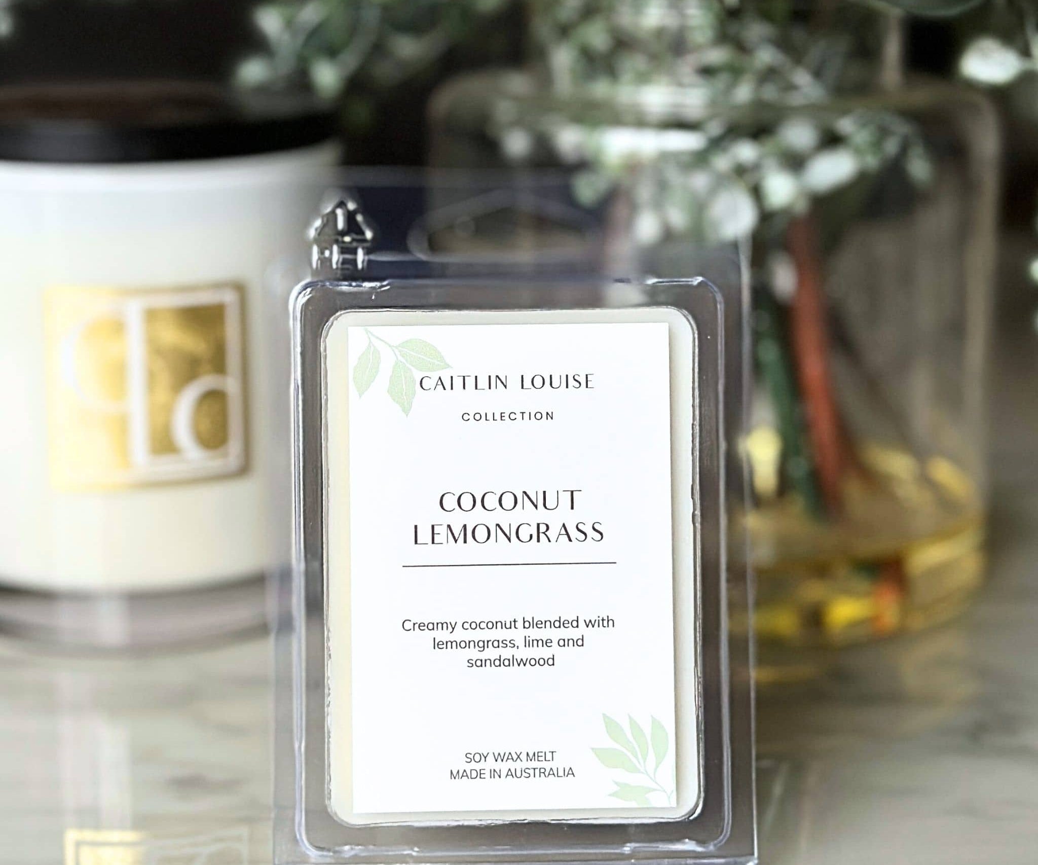Coconut Lemongrass wax melt packaging with a blurred background of candles and plants