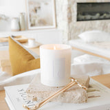 Caitlin Louise Collection Core Candle on book with lounge room and fireplace in background.