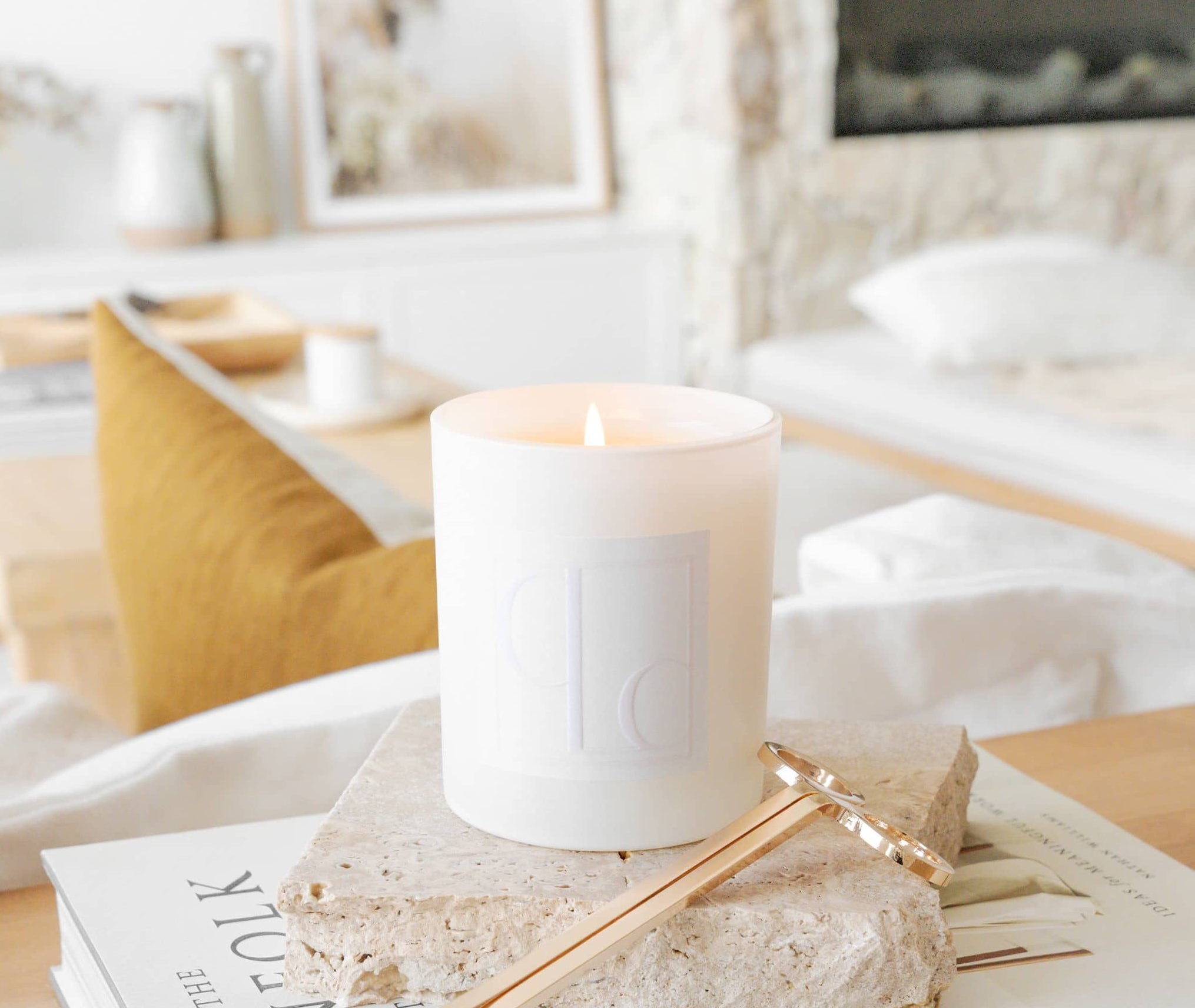 Caitlin Louise Collection Core Candle on book with lounge room and fireplace in background.