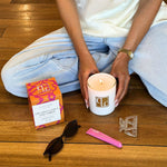 Person holding a lit candle next to the box on a wooden floor.