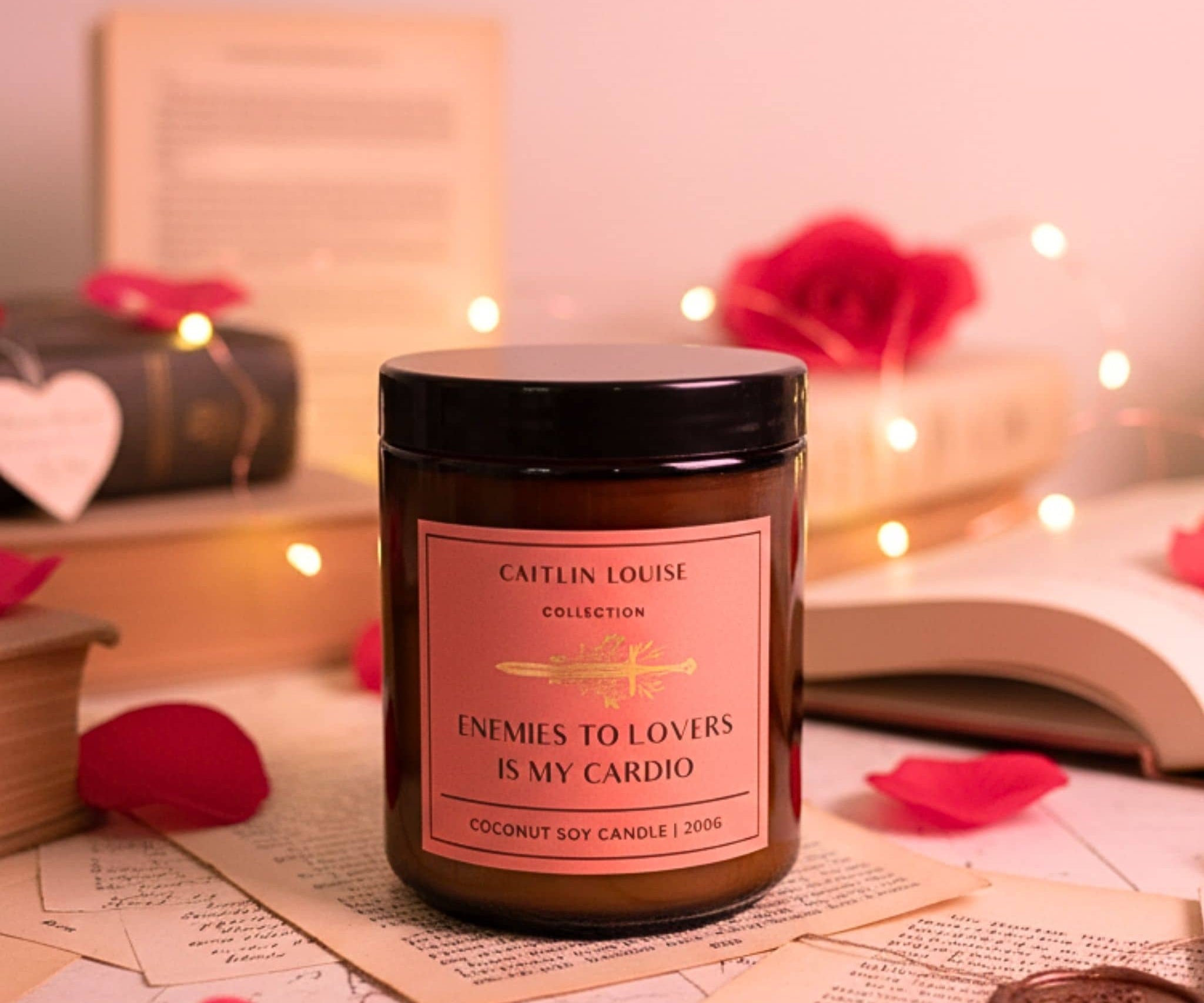 Candle with a pink label on a surface with books and heart-shaped objects