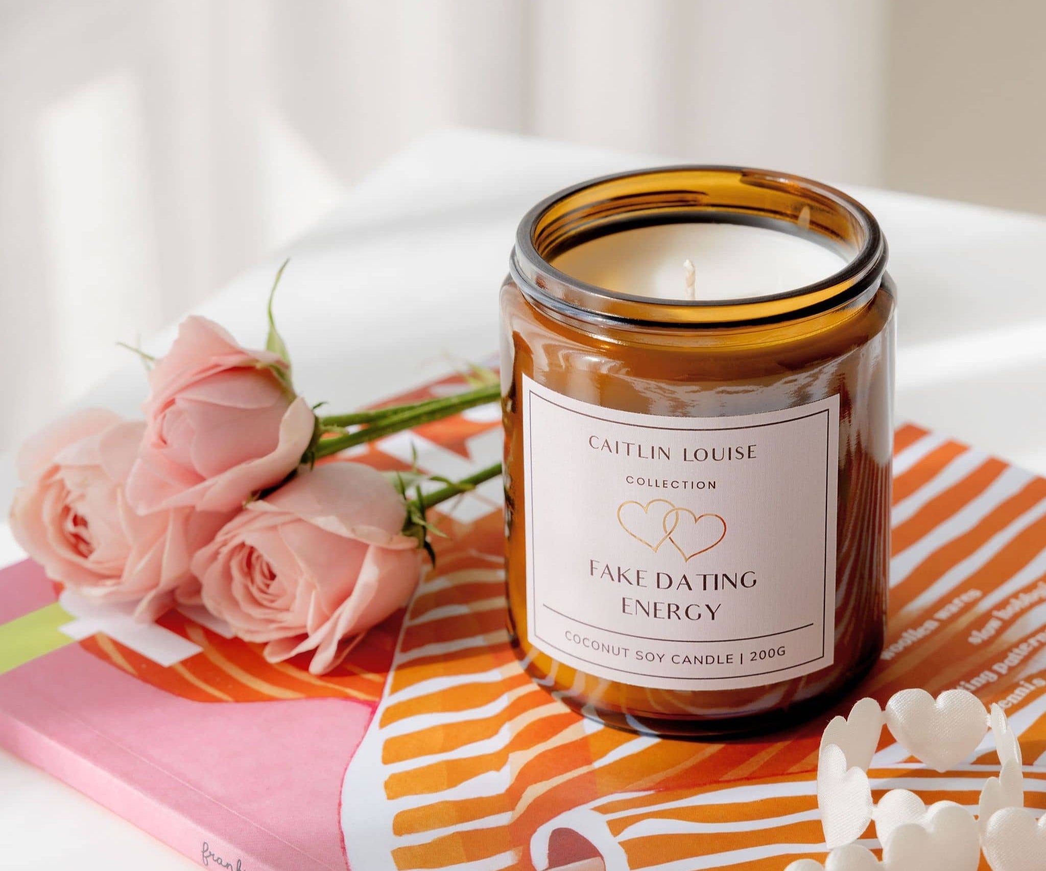 Candle labeled 'Fake Dating Energy' with pink roses on a colorful surface