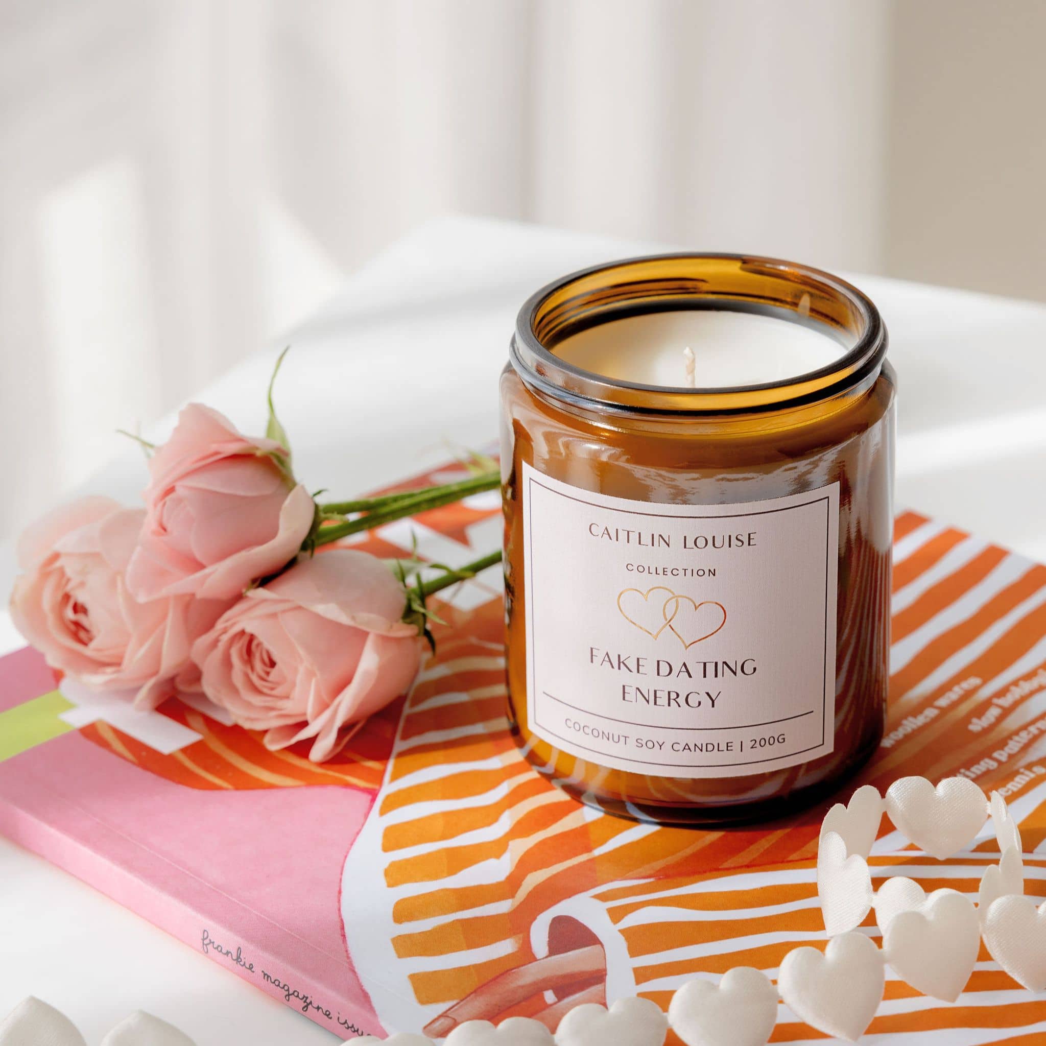 Candle labeled 'Fake Dating Energy' with pink roses on a colorful surface
